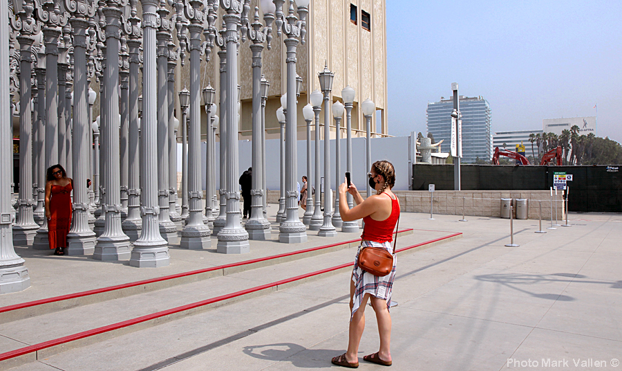 "Selfies." In the background you can see wrecking cranes and tractors pulverizing LACMA into dust, as people take selfies at the Urban Light "sculpture." Photo Mark Vallen ©. May 13, 2020